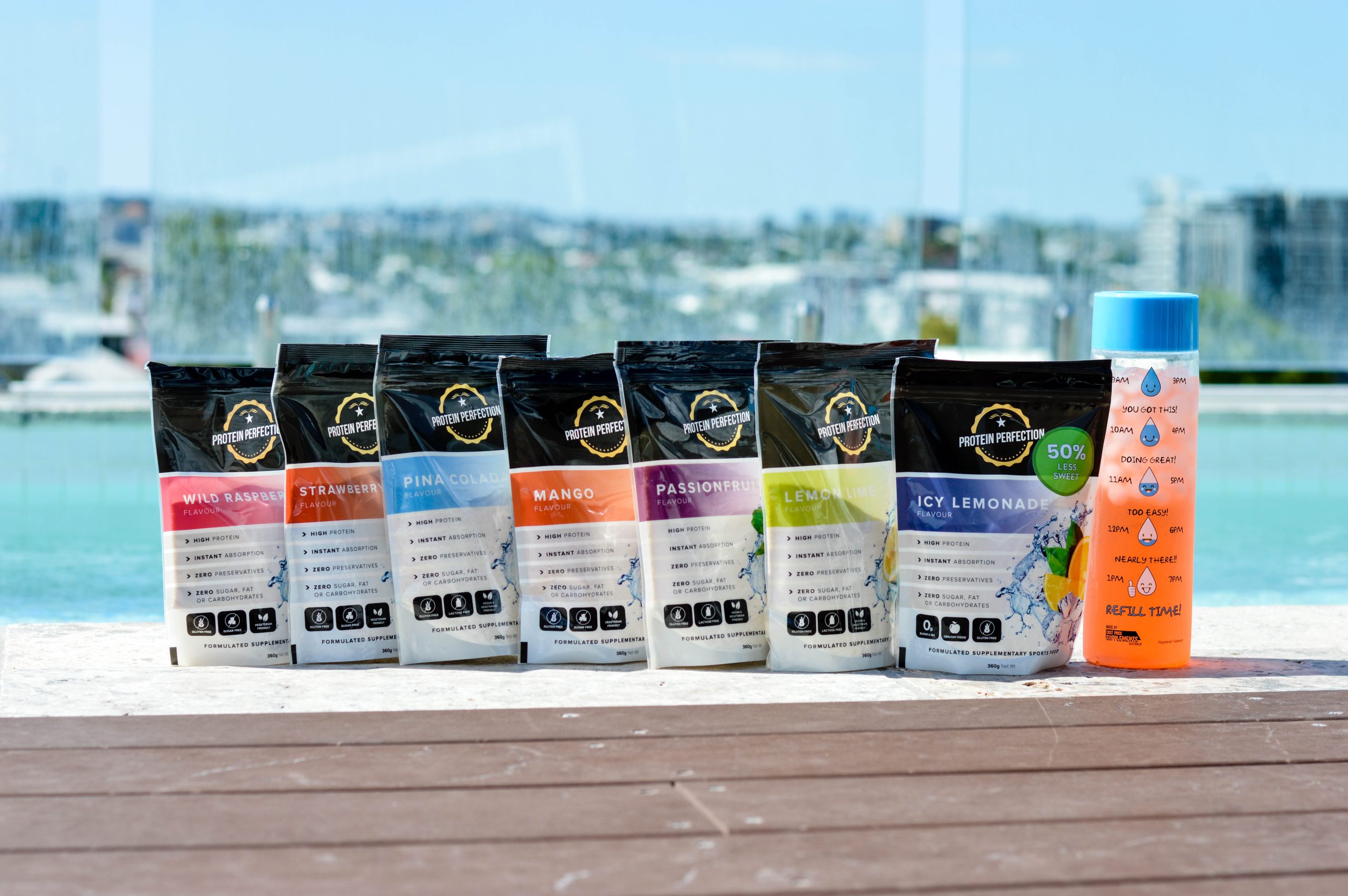 An Image of all 7 flavours of protein perfection protein water bariatric bottle by the sea