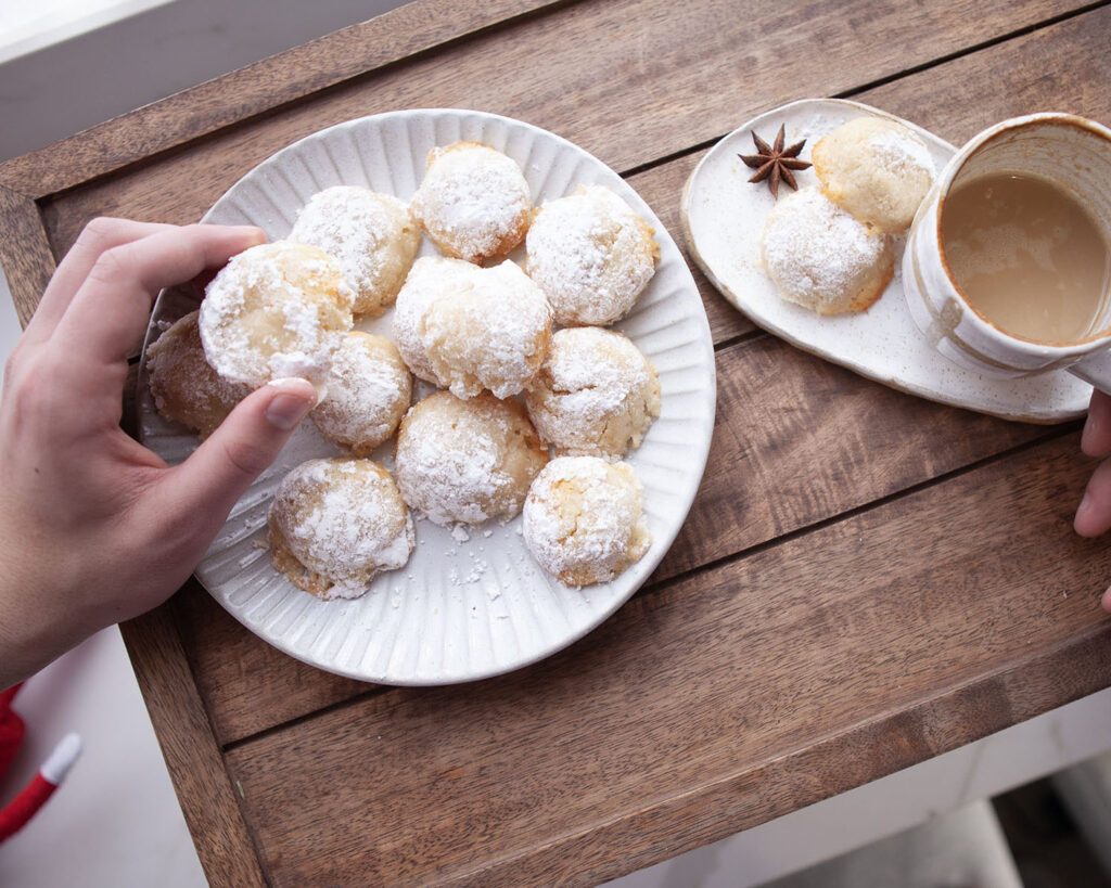 Hands Picking Almond Vanilla Protein Cookies and Hot Beverage