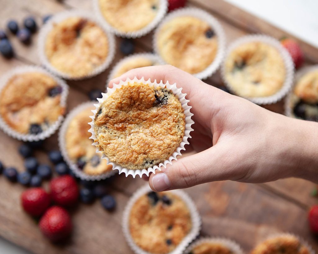 Hand Grabbing Lemon Blueberry Protein Muffins