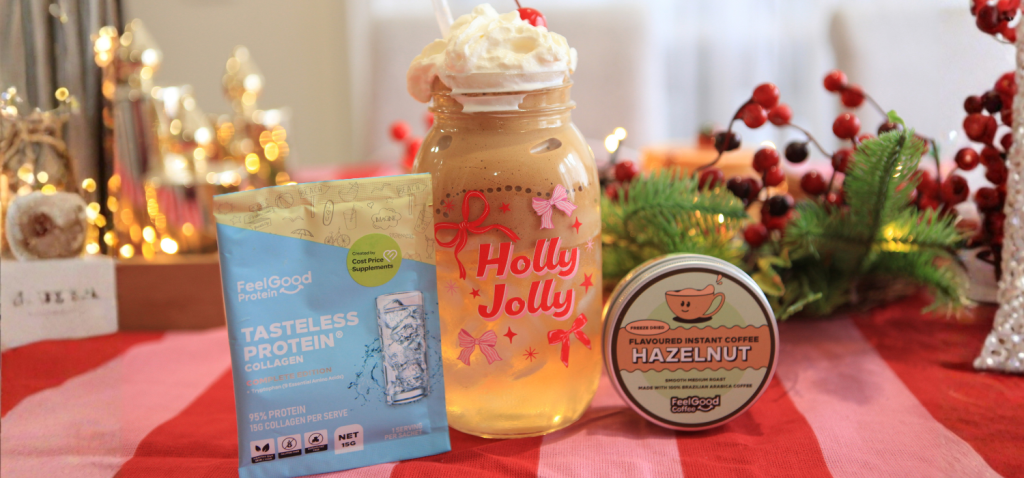 Photograph of items on table from left to right: Tasteless Protein Collagen sachet, Coconut Hazelnut Cloud Proffee in tall glass reading 'Holly Jolly', Flavoured Instant Coffee by Feel Good Coffee (Hazelnut) in a tin