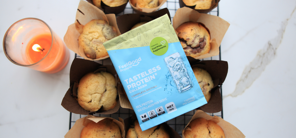 Wooden board topped with high-protein double chocolate muffins, with a sachet of Feel Good Protein Tasteless Collagen resting on top