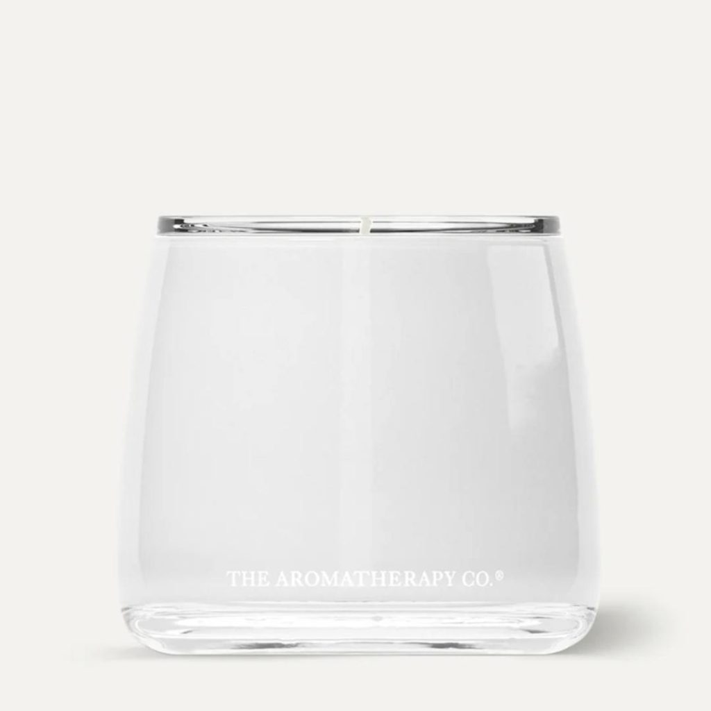 A white aromatherapy candle displayed on a simple neutral backdrop.