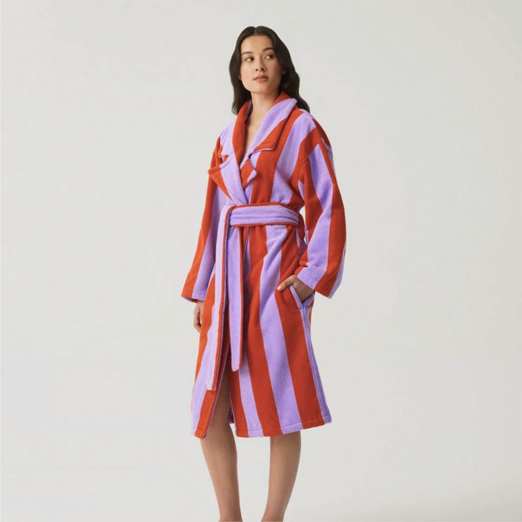 A model posing in a vibrant purple and red striped Hommey robe