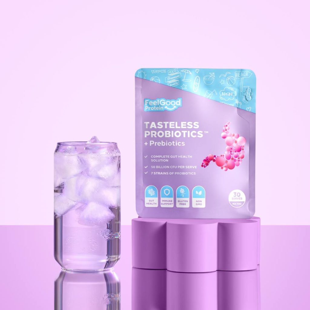 A purple and blue packet of Tasteless Probiotics and Prebiotics by Feel Good Protein displayed on a purple pillar beside a glass of iced water.