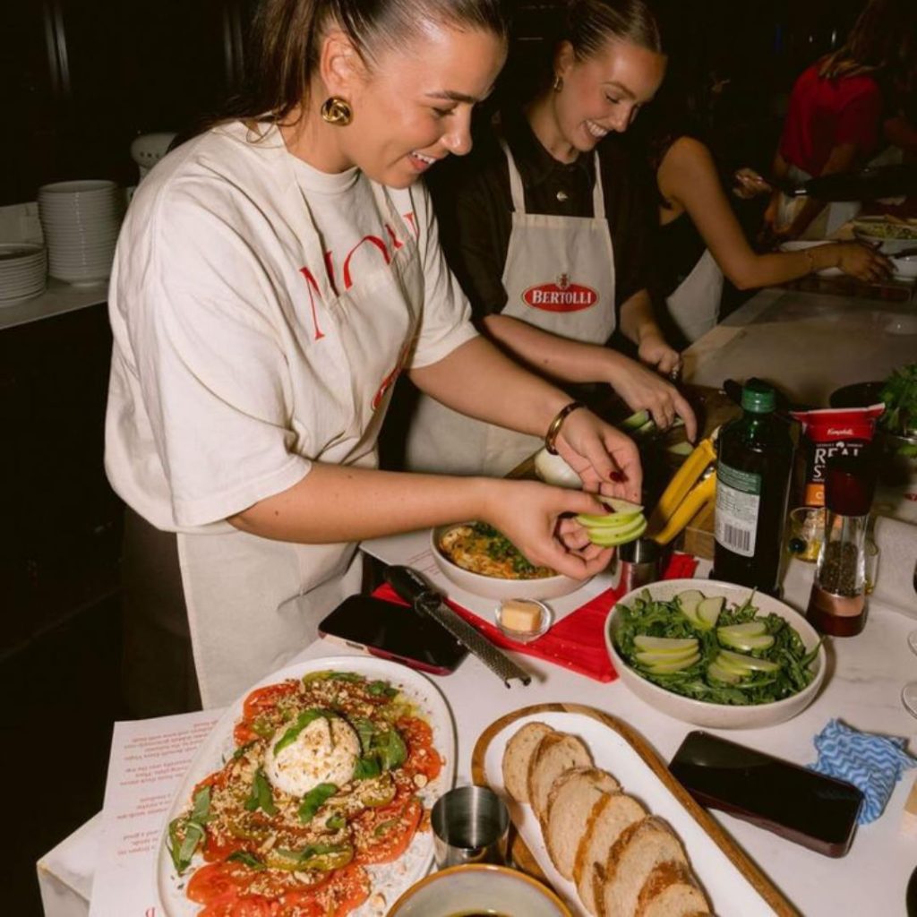 Two women in a cooking class preparing a fresh salad together.