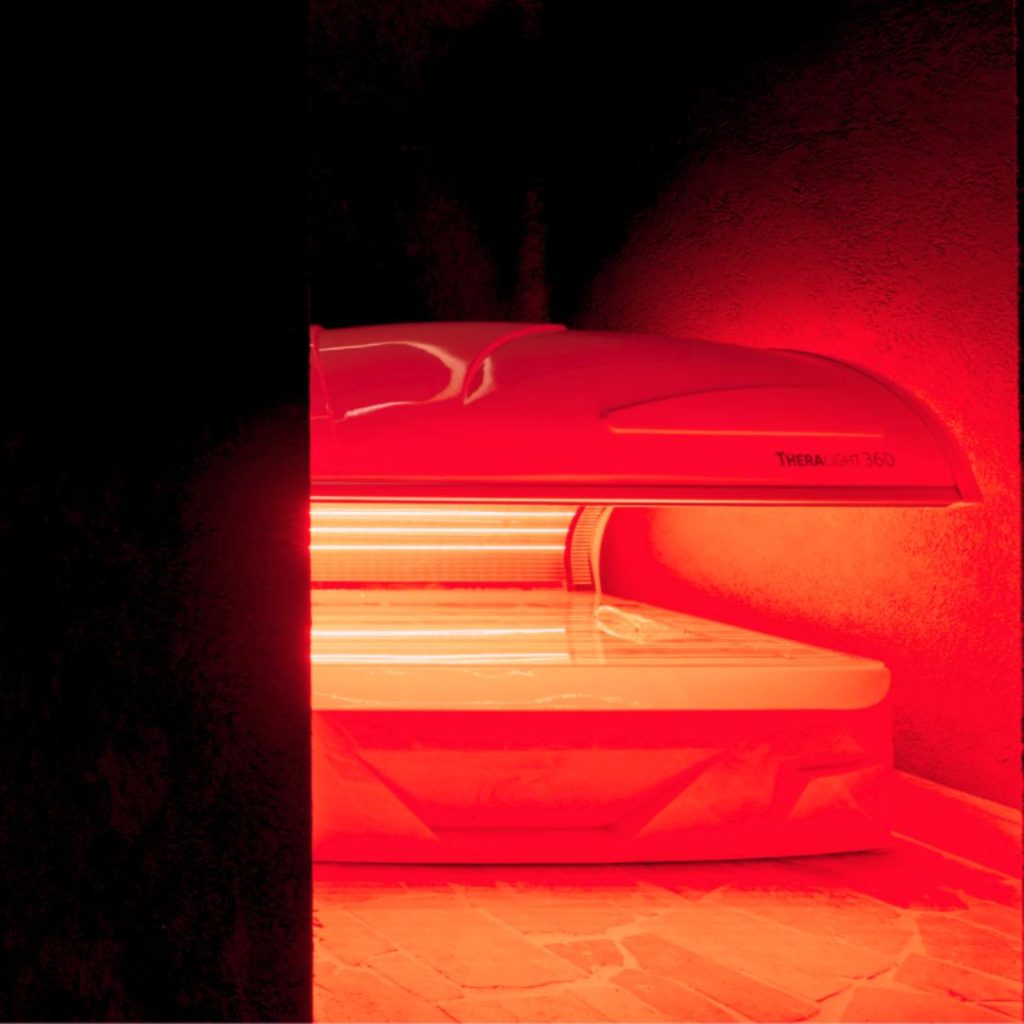 A red and black close‑up photo showing half of a red light sauna machine at Total Fusion.