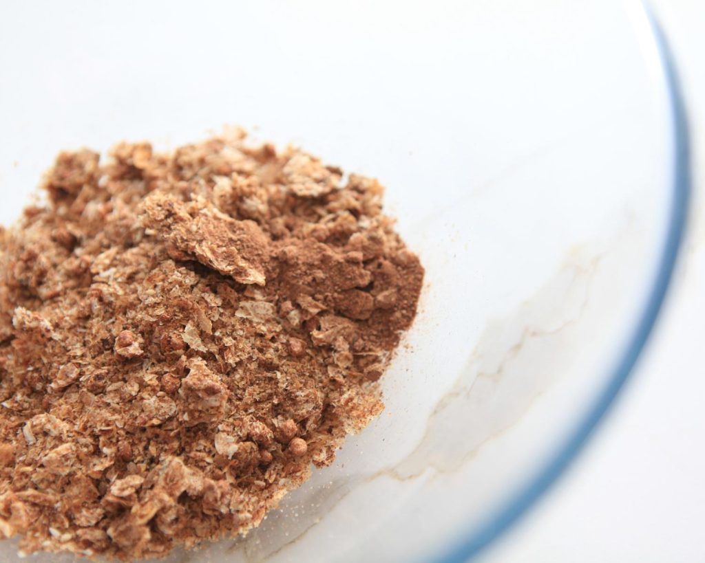 Crumbled Weet‑Bix sitting in a clear glass mixing bowl, photographed from above