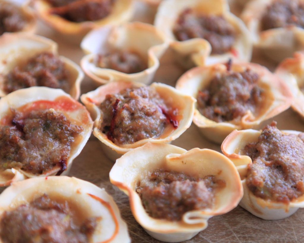 13 Beef Dumpling Cups arranged in rows on a wooden board in a close-up view.