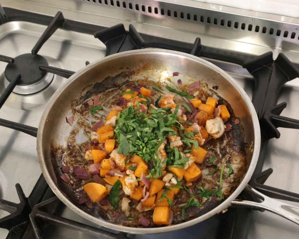 An image of the sliced baby spinach being added to the BBQ Chicken & Sweet Potato Muffins recipe