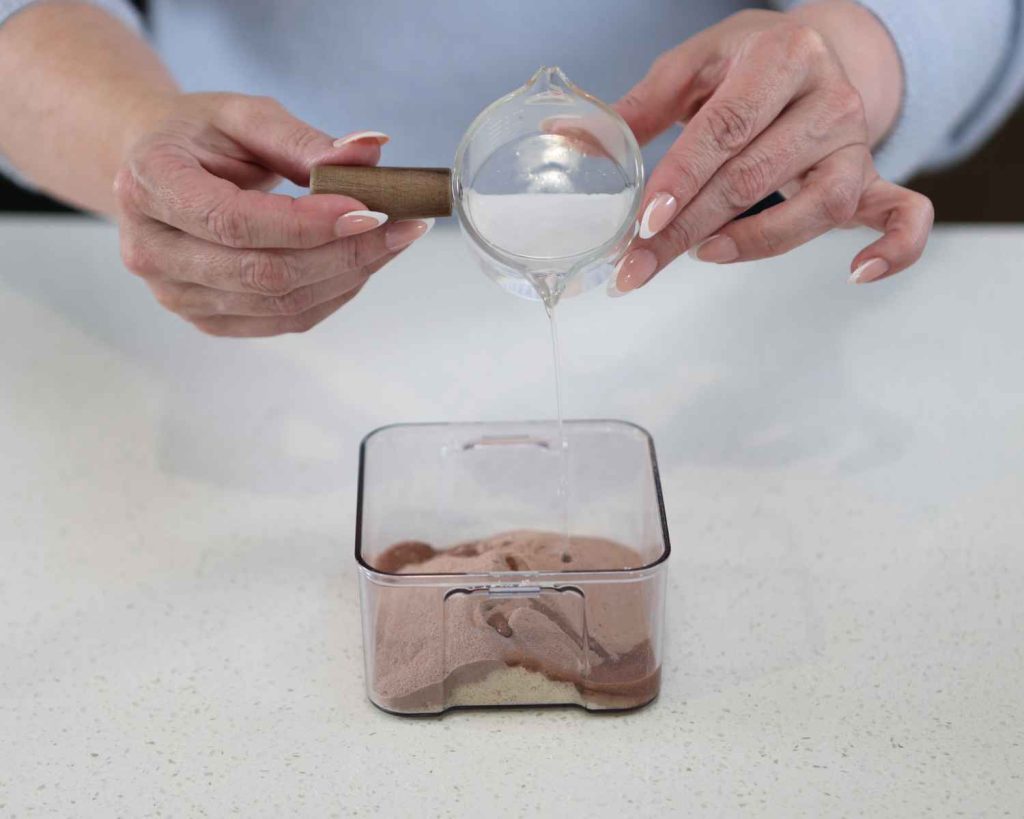 Adding water to the whey protein and almond mix for the St Patrick’s Day Protein Cheesecake recipe