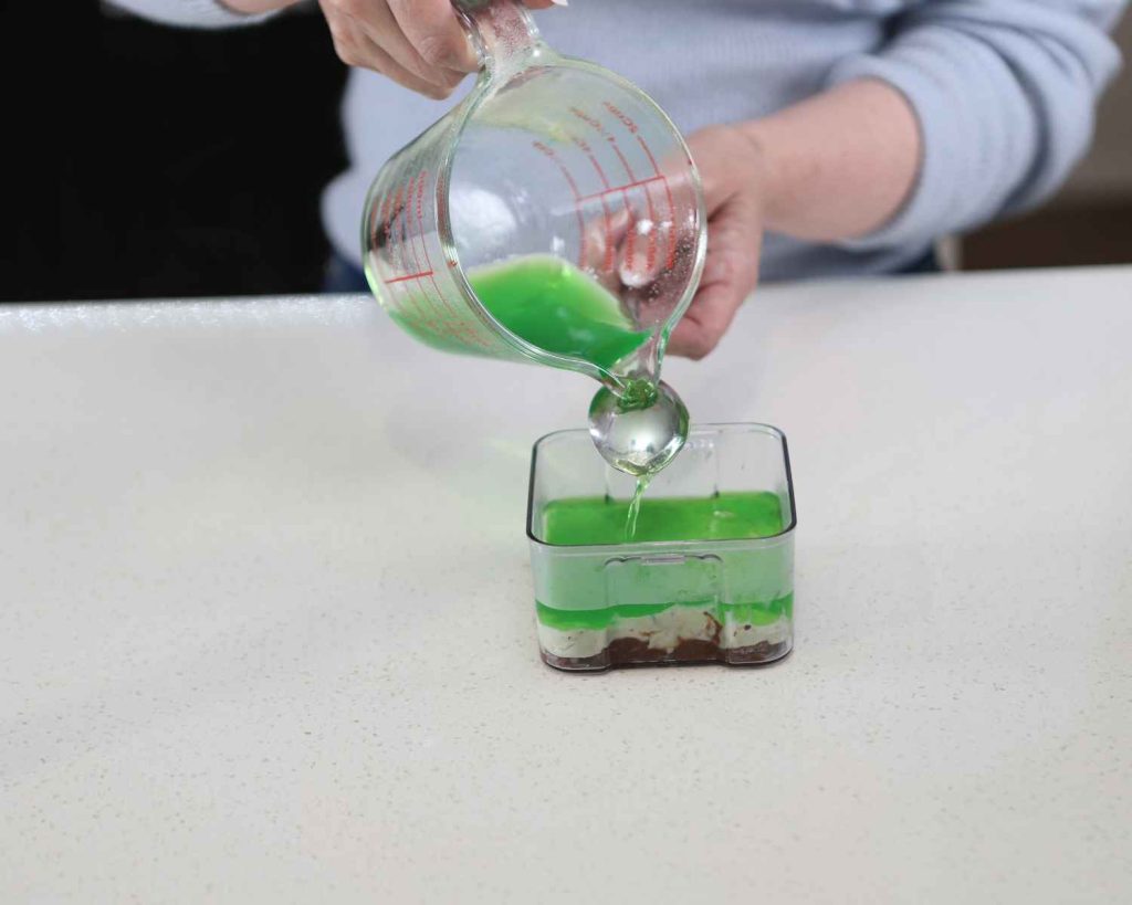 Adding the protein jelly over the yoghurt for the St Patrick’s Day Protein Cheesecake recipe