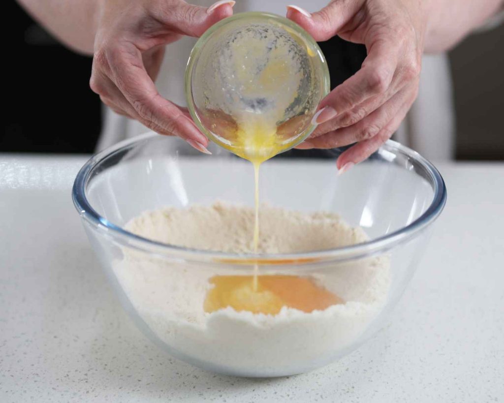 Adding the melted butter into the ingredients bowl to create the Chocolate Chunk Protein Cookies recipe