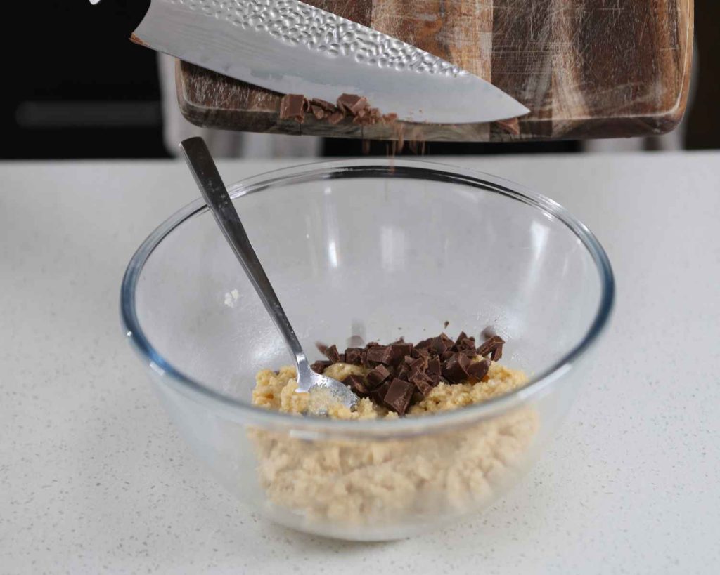 Adding the chopped chucks of milk chocolate to create the Chocolate Chunk Protein Cookies recipe