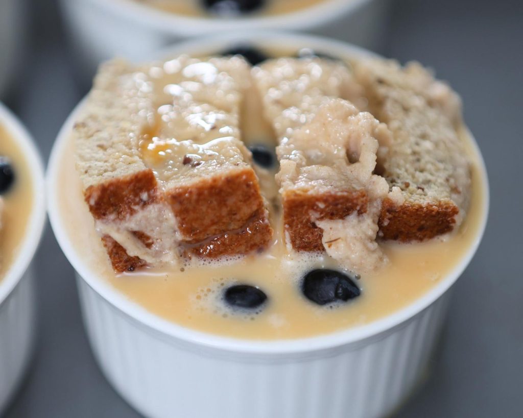 Close up shot of a ramekin filled with unbaked Blueberry French Toast Protein Cup mixture, placed on a baking tray.