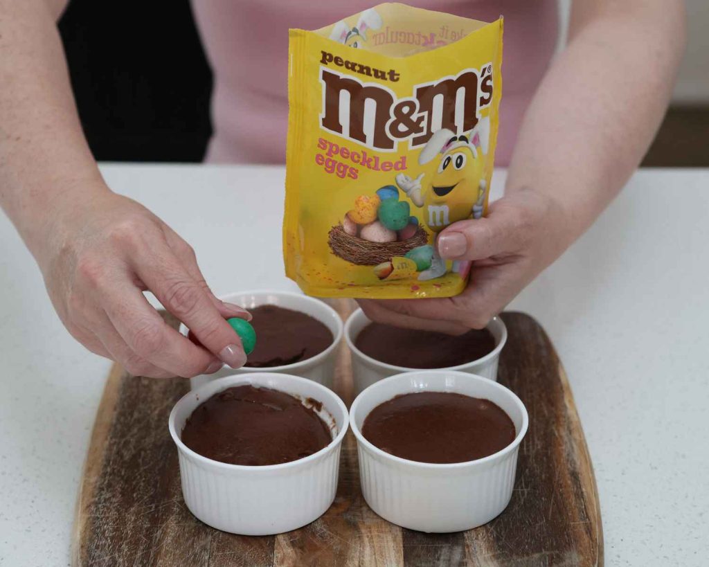 Adding M&M’s Peanut Milk Chocolate Speckled Easter Eggs to the cheesecake for the Mini Chocolate Protein Cheesecake recipe