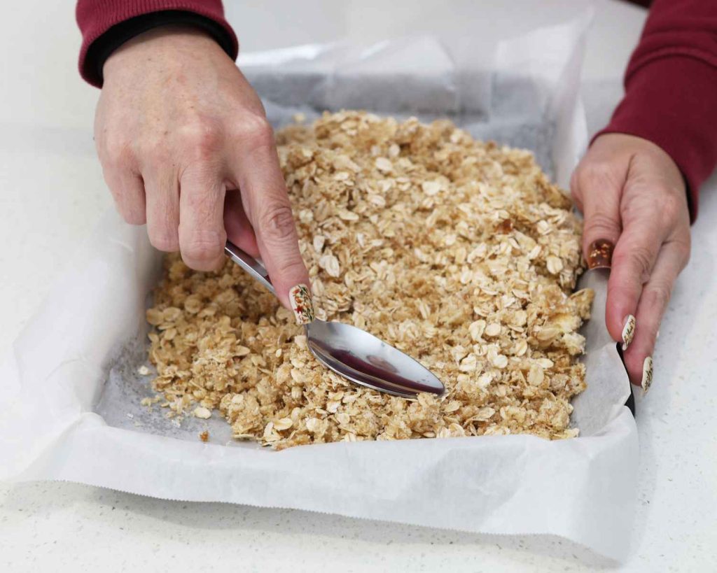 Patting down the mixture in the tin