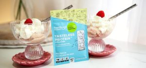 Front-facing photo of two glass bowls of Raspberry Swirl Protein Ice Cream with a blue and yellow sachet of Tasteless Protein Collagen by Feel Good Protein in the centre, with a softly blurred modern kitchen in the background.