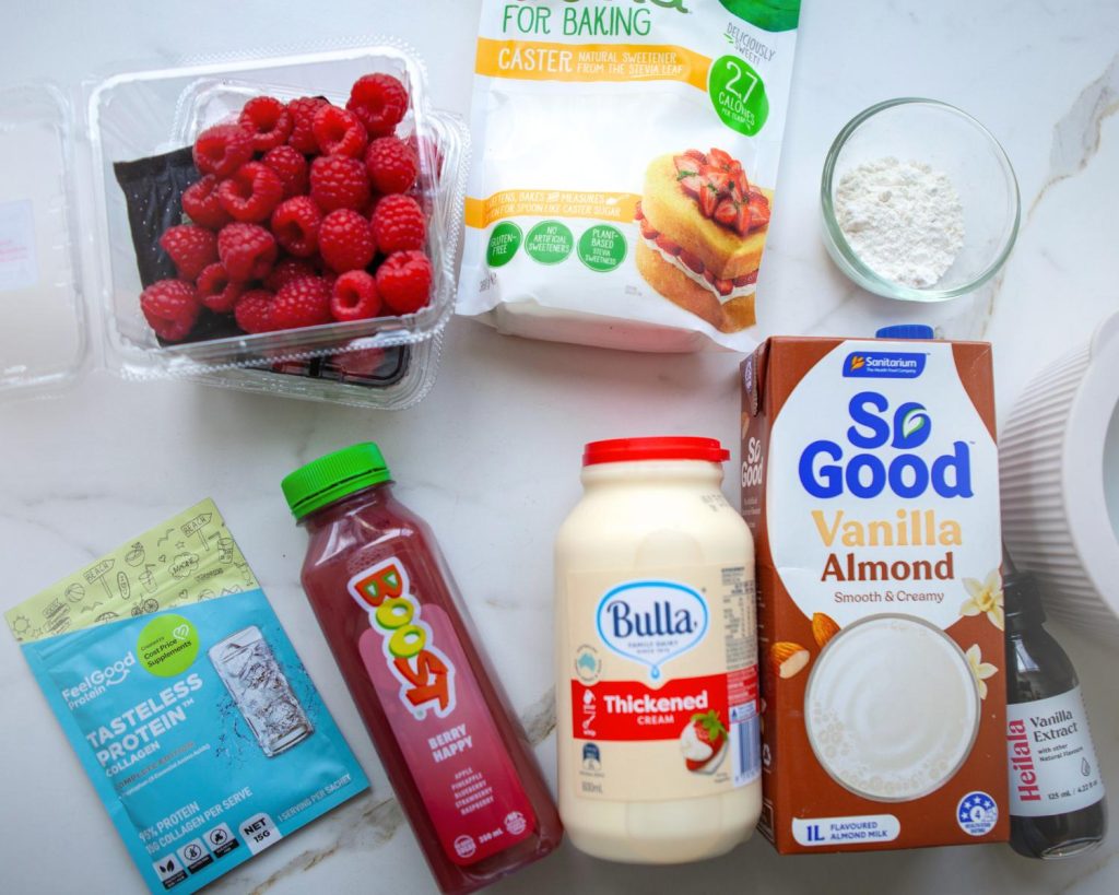 Top down photo showing all the ingredients for Raspberry Swirl Protein Ice Cream arranged side by side on a benchtop, with a white bench in the background. 