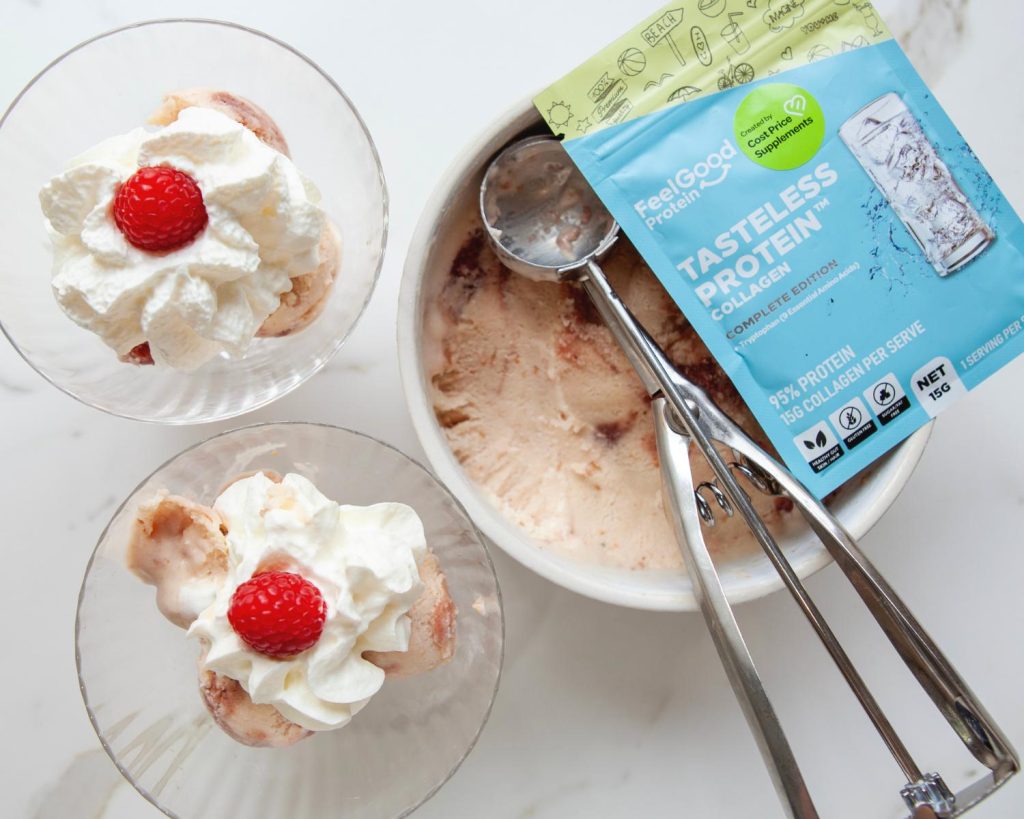 Top-down photo of a large white bowl filled with Raspberry Swirl Protein Ice Cream with a sachet of Tasteless Protein Collage by Feel Good Protein on top, next to two small glasses of Raspberry Swirl Protein Ice Cream, topped with whipped cream and raspberries. 