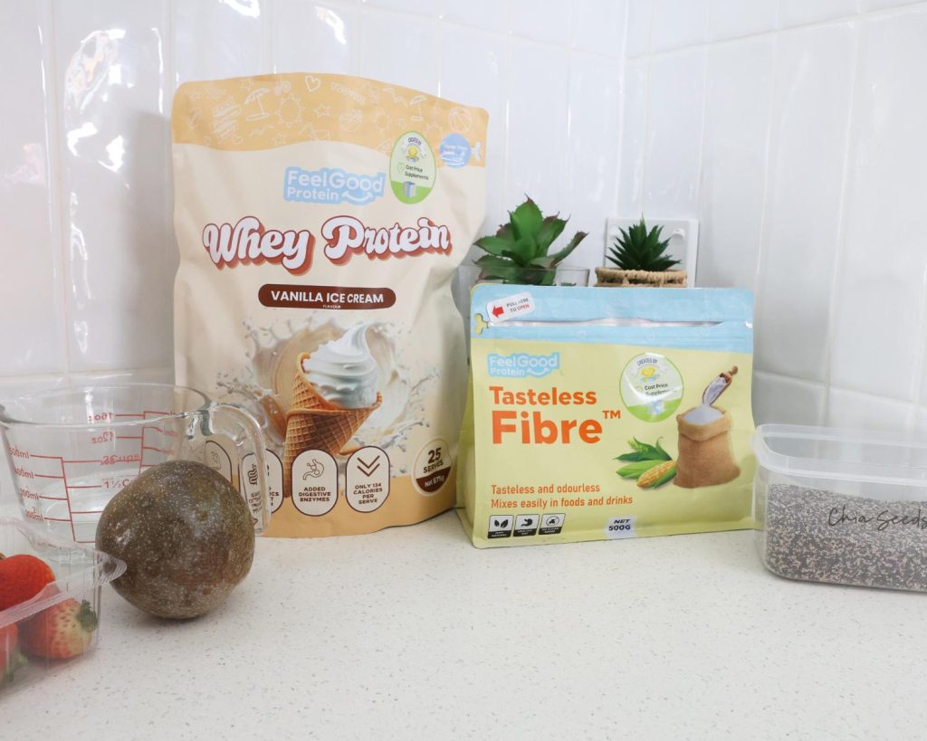 Front-facing photo showing all the ingredients for High Protein Vanilla Ice Cream Chia Pudding side by side on a benchtop, with a softly blurred modern kitchen in the background. 