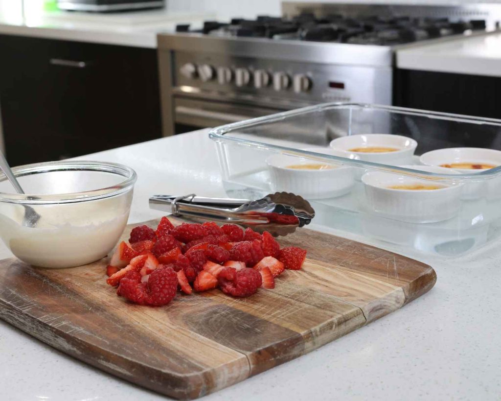 Topping the baked custard with the creme fraiche and chopped strawberries and raspberries
