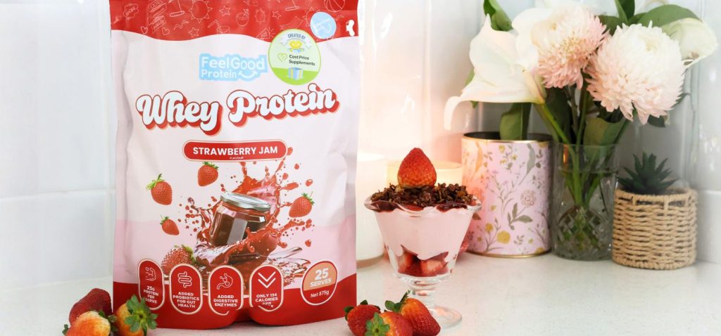 Front on photo of a red and pink back of Whey Protein by Feel Good Protein (Strawberry Jam) on the left of a Strawberry Cheesecake Protein Bowl placed on a kitchen bench.