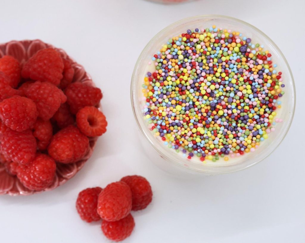 Photo of a glass bowl of High Protein Viral Dot Cake placed next to a bowl of fresh raspberries. 